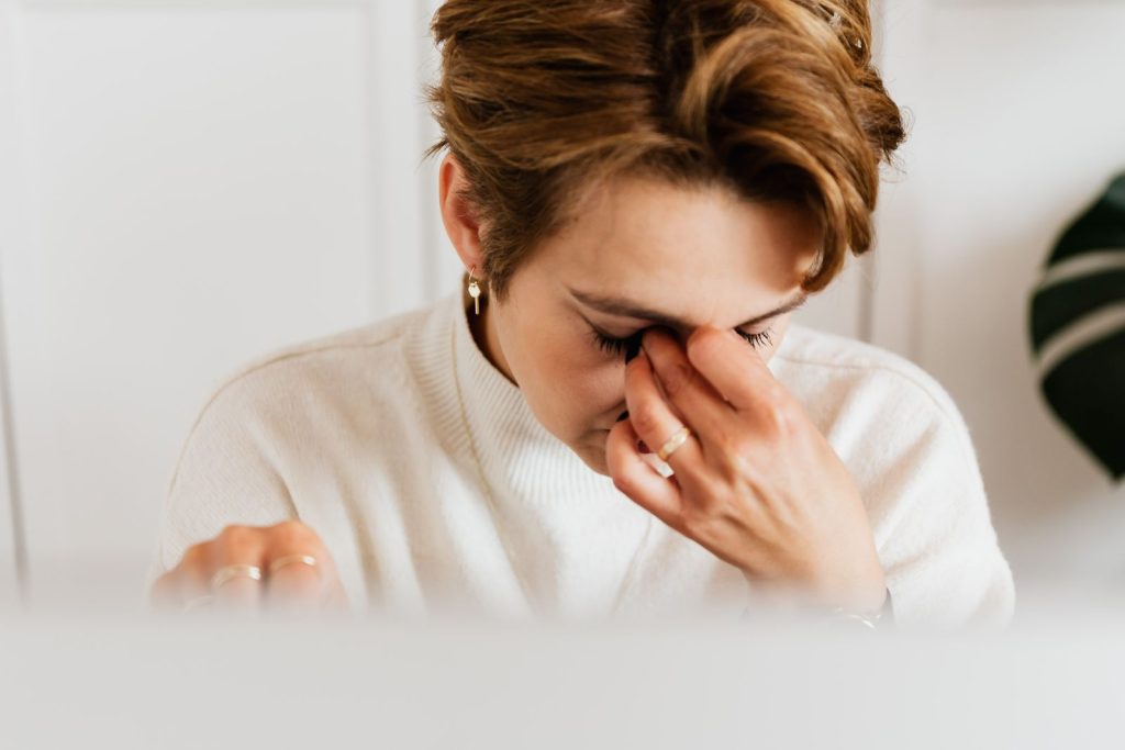 Frau reibt sich die juckenden Augen, typisch für eine Allergie
