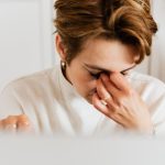 Frau reibt sich die juckenden Augen, typisch für eine Allergie