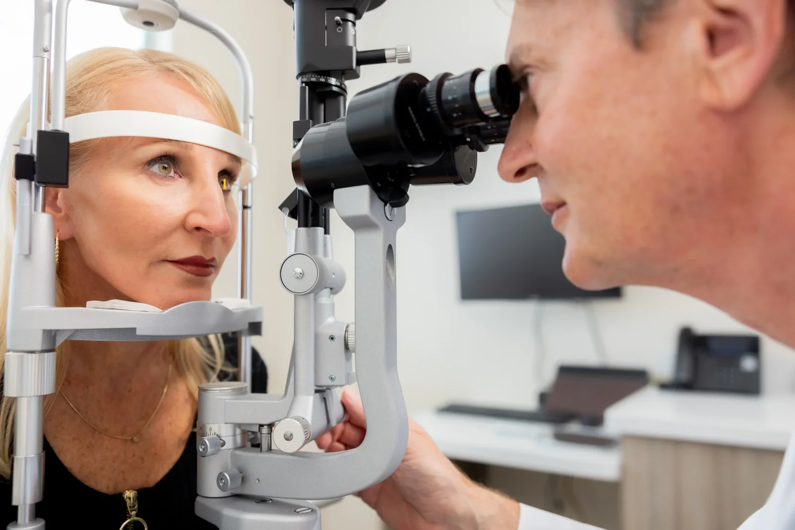 Eine Patientin sitzt an der Spaltlampe, während der Augenarzt ihre Augen untersucht